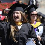 A graduaten smiling and waving.