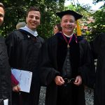 Four male graduates stand together for a photo