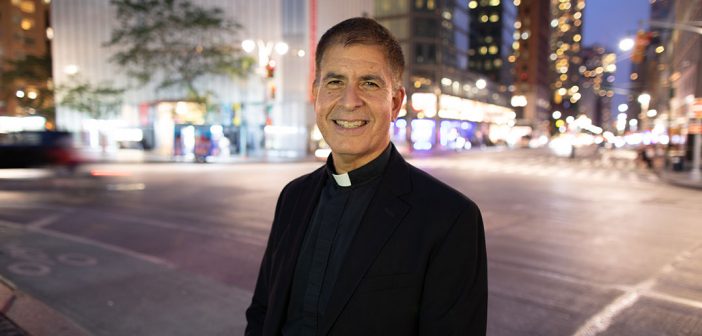 Father John Cecero in Columbus Circle at dusk, with streetlights