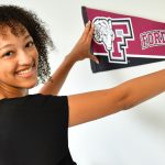 woman student posting Fordham bannner on wall