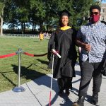 A blind graduate is helped down the aisle by a friend.