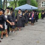 Group of women graduates lean forward with outstretched arms to pose for a picture