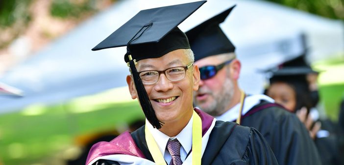 A male graduate with classes smiling