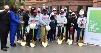 Joseph M. McShane stands with students and diginitries wearing hard hats and holding shovels