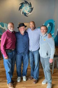 Claude Mangum, Mark Naison, Mark L. Chapman, and Bill Kiernan posing at Sand City Brewing.