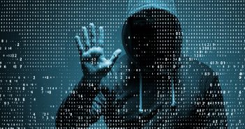 A man wearing a hood with his face hidden presses his palm against a transparent screen, while numbers swirl around him.