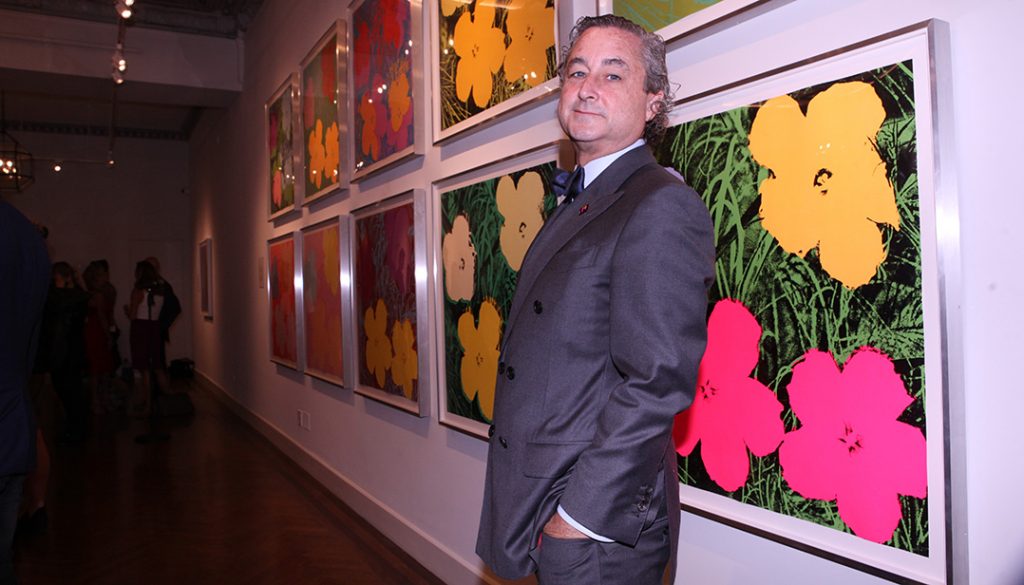Raymond Dowd stands before Warhol's "Flowers" series at the opening of National Arts Club show. 