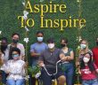 A group of masked students pose under a sign that says "Aspire To Inspire."