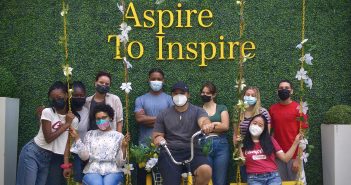 A group of masked students pose under a sign that says "Aspire To Inspire."