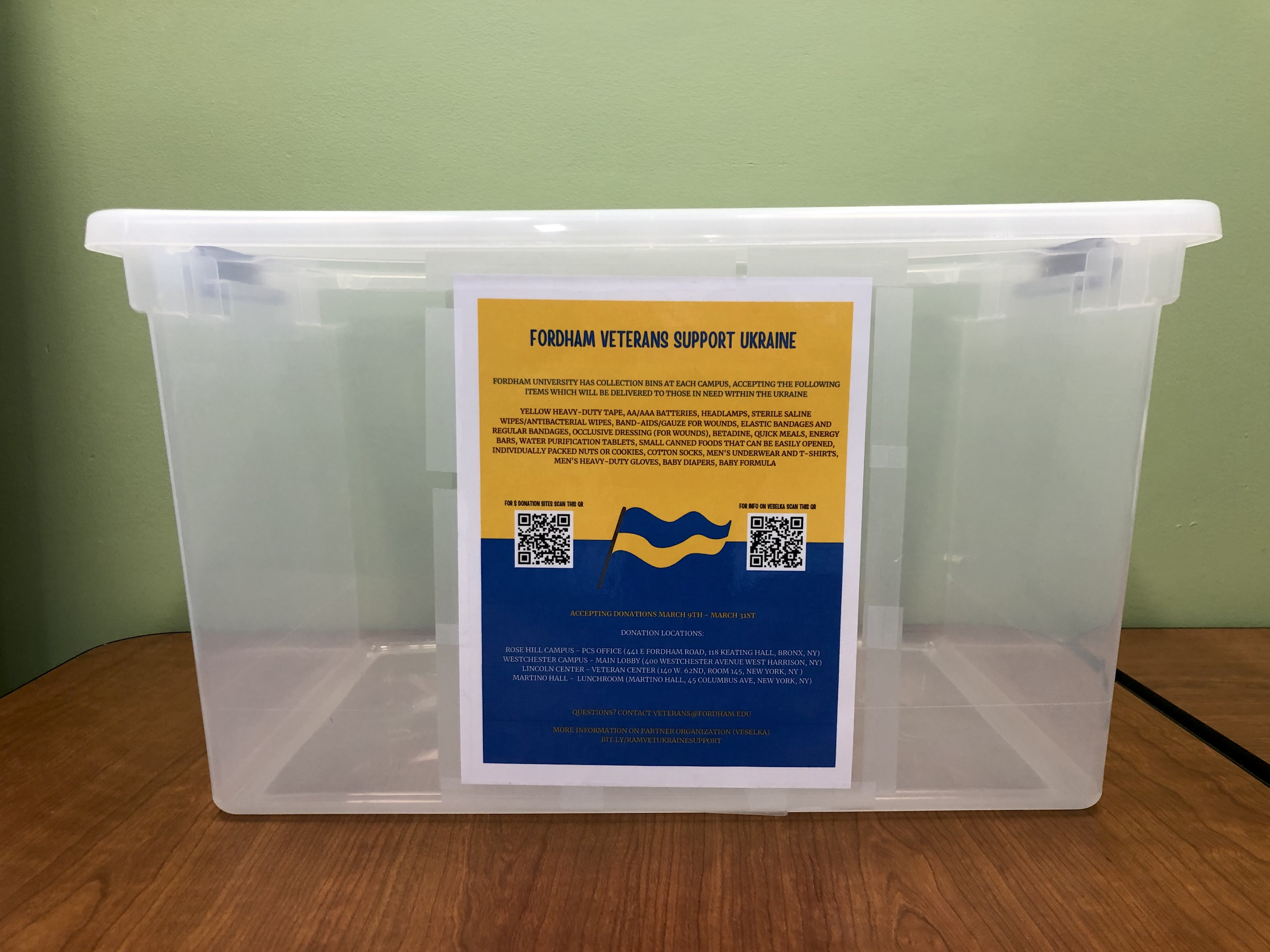 A plastic empty bin with a yellow and blue flyer attached to the front