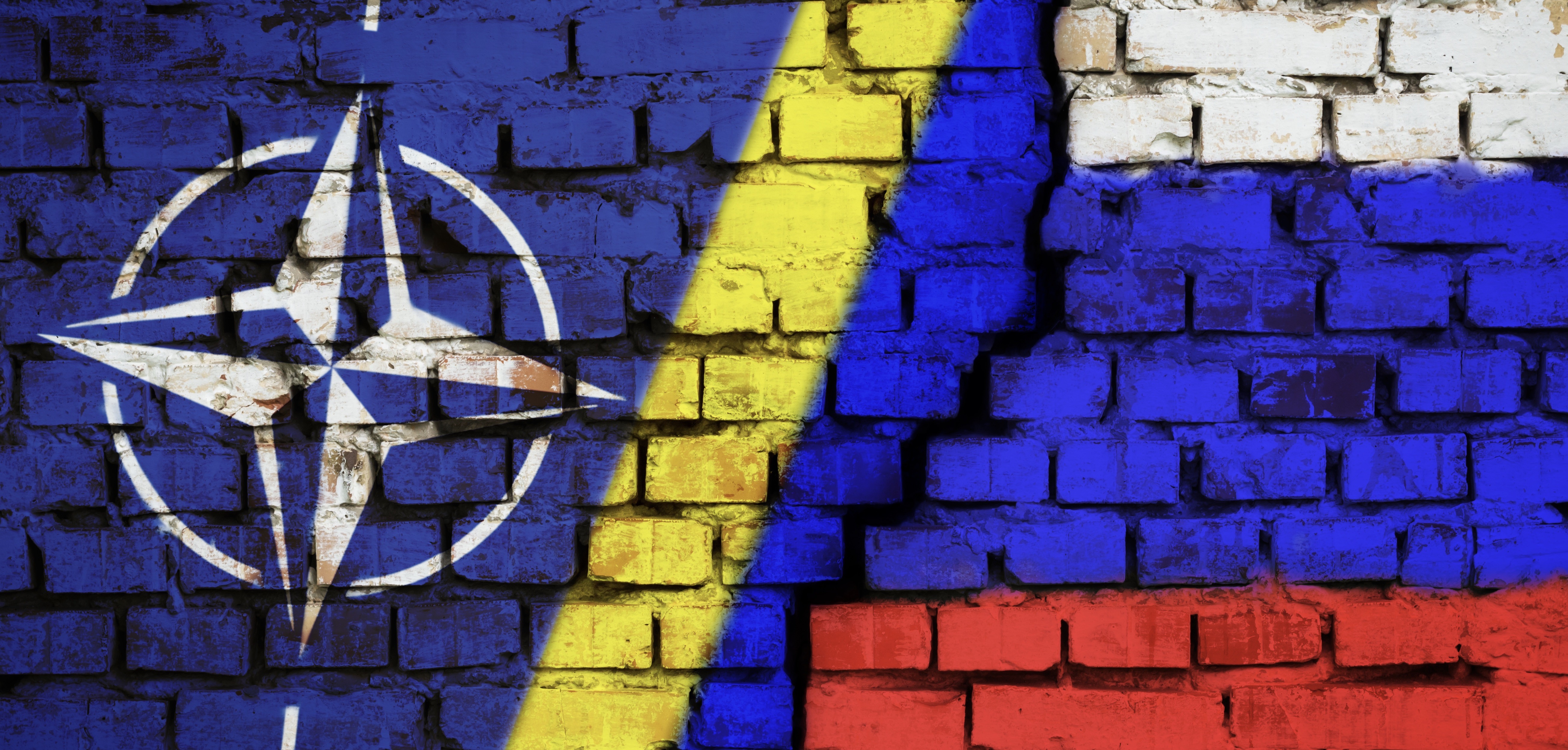 Cracked brick wall with the patterns of the NATO, Ukraine, and Russian flags