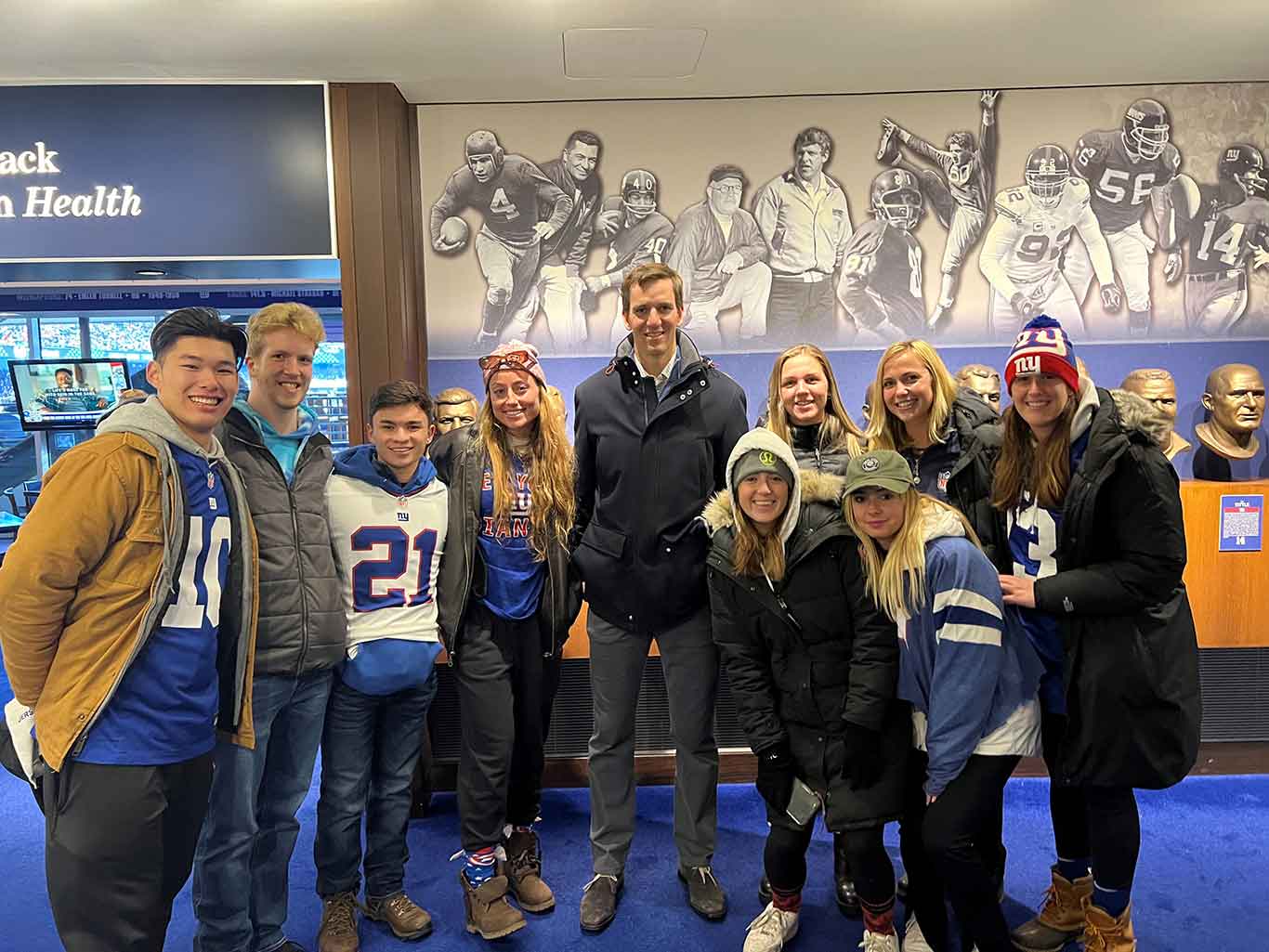 Fordham students standing with Giants quarterback Eli Manning