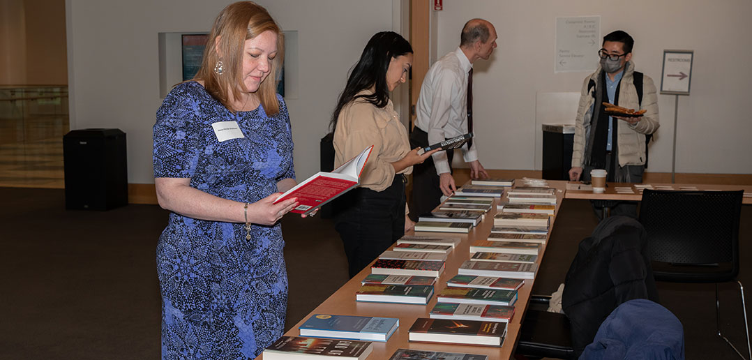 A woman reading one of several books laid out on display