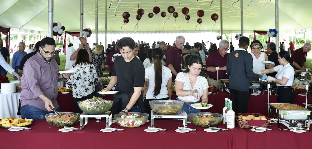 A group of people gather food from a buffet.