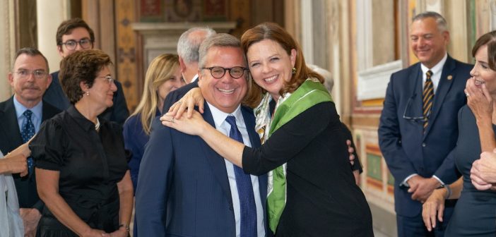 A woman embraces a man, who are both smiling.