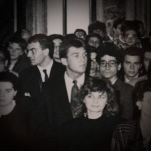 A black and white photo of a man standing in a crowded group.