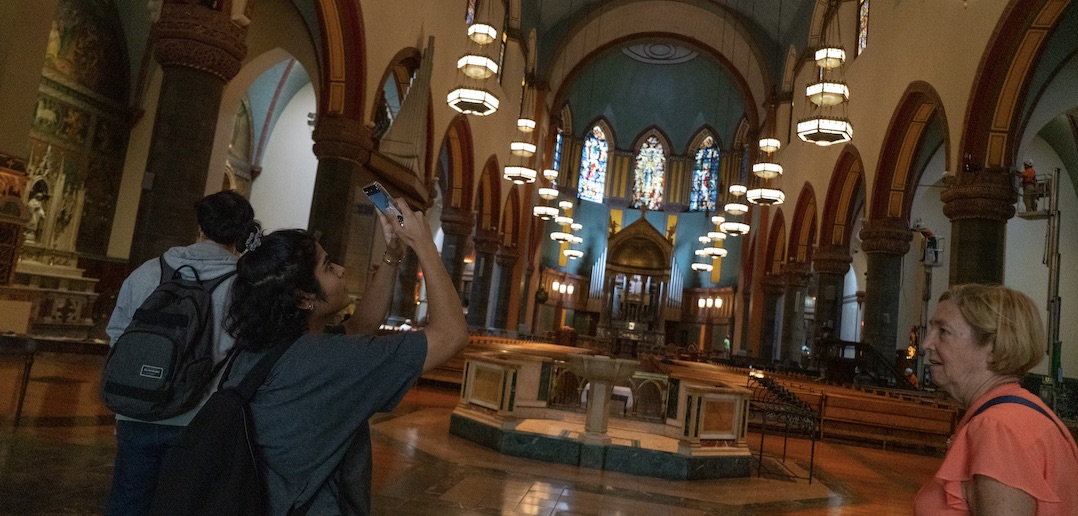 A woman takes a photo with her phone inside a dimly lit church.