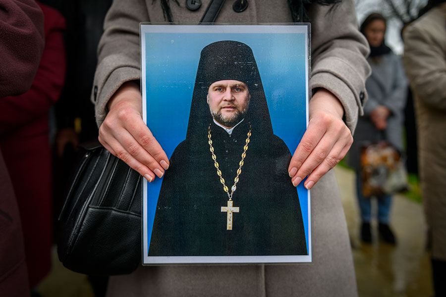A mourner holds a portrait of Father Zvarychuk, who was buried near his mother in his native village in western Ukraine.