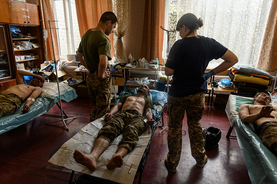 Ukrainian soldiers lying on cots in a field hospital