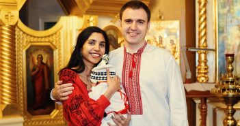 Fordham graduates Priya and Alex hold their infant son, Neil, in 2019 following Neil's baptism in St. Michael's Golden-Domed Cathedral in Kyiv.