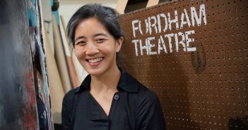 A woman smiles next to a "FORDHAM THEATRE" sign.