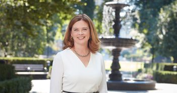 A portrait of Fordham President Tania Tetlow outside Cunniffe House with Cunniffe Fountain in the background