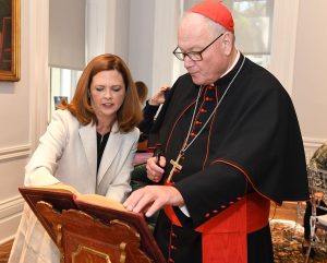 Tania Tetlow stands with Cardinal Dolan as he signs a guest book.