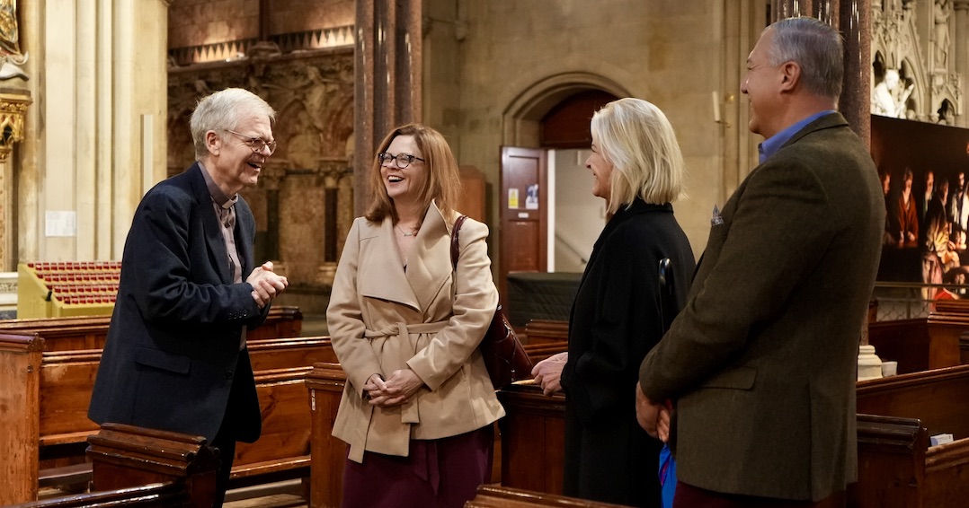 Four people stand and chat in a church.