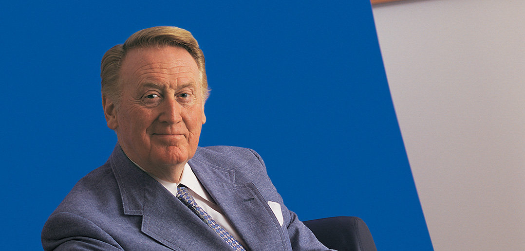 Vin Scully, Fordham graduate and Hall of Fame broadcaster, seated against a blue background