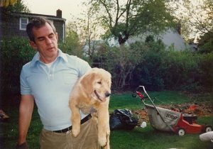 Monsignor Shelley holding a Susie, a golden retriever, in 1980