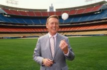 Vin Scully stands in the outfield at Dodgers Stadium in 1987 tossing a baseball into the air