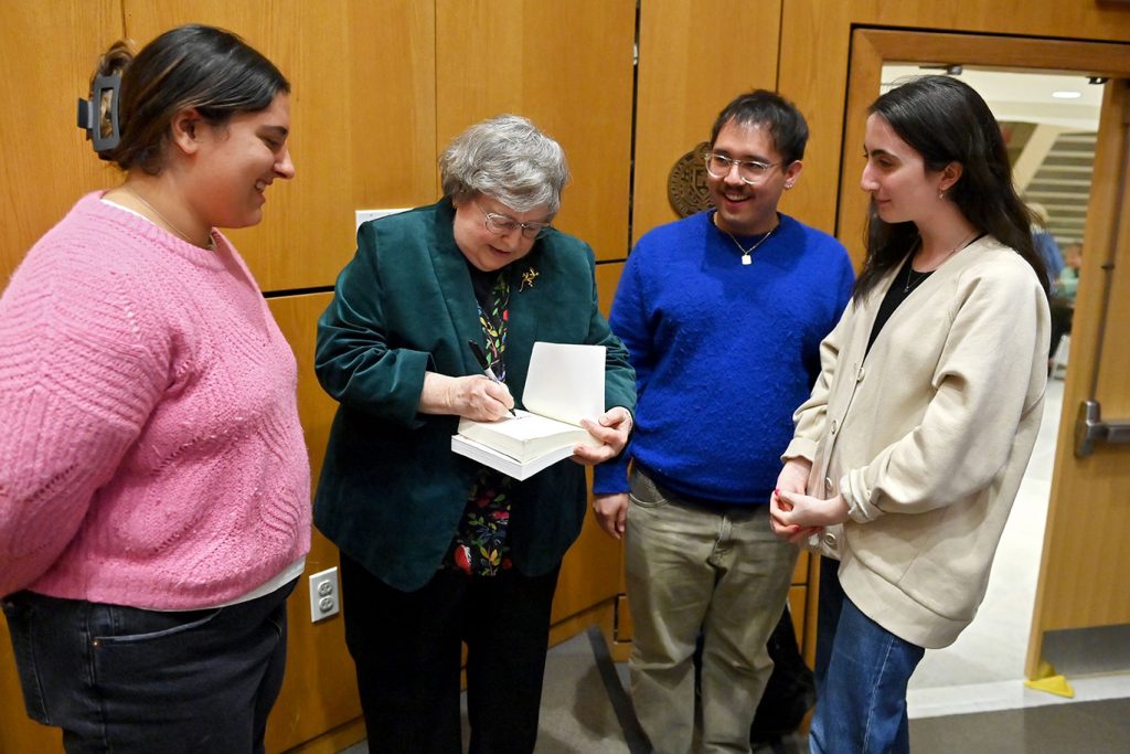 Students surround Elizabeth Johnson as she signs a book