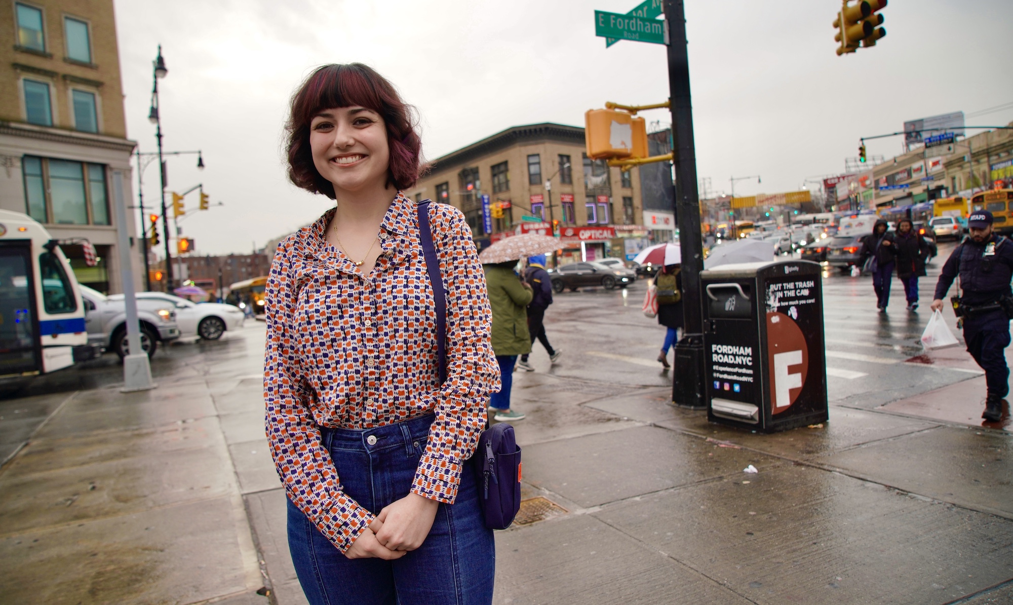 A girl stands and smiles in front of a busy street.