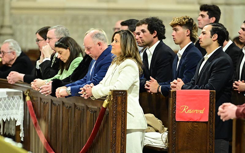 People kneel in the first few pews of St. Patrick's Cathedral during a Mass in memory of Vin Scully