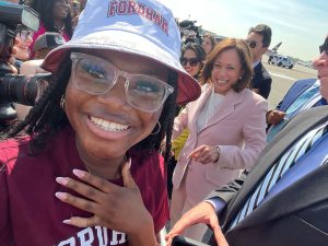 Claudia Dabie pses for a selfie with Kamala Harris behind her.