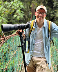 Michael Patrick Davidson stands with camera in hand amid the rainforest canopy on Borneo