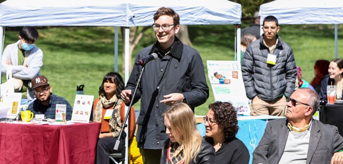 A young man with glasses speaks into a microphone