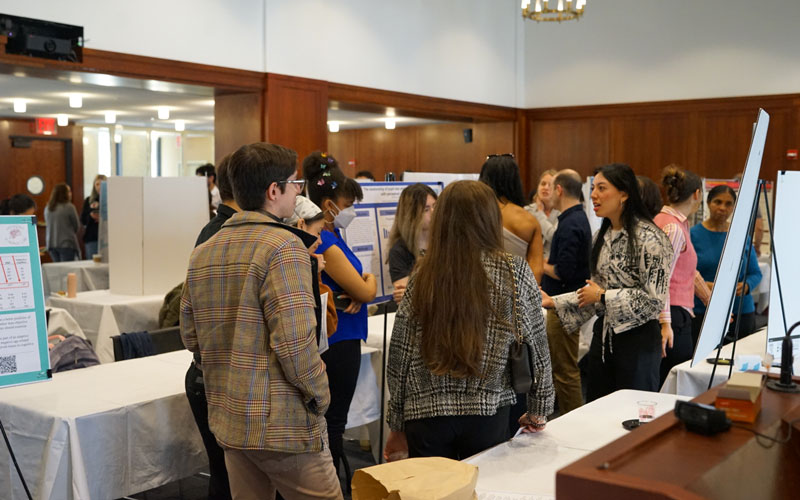 People stop by posters at a research fair