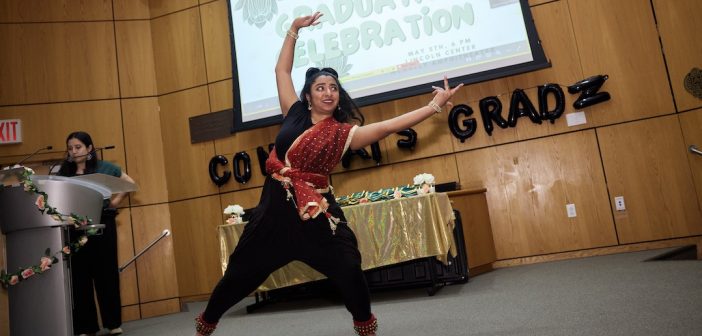 A woman wearing traditional South Asian attire dances.