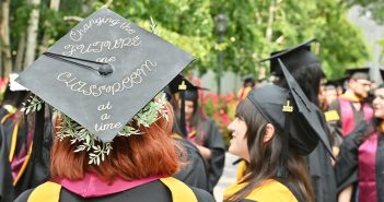 A GSE graduate wearing a cap that says, "Changing the future one classroom at a time."