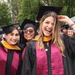 women grads smiling and touching caps