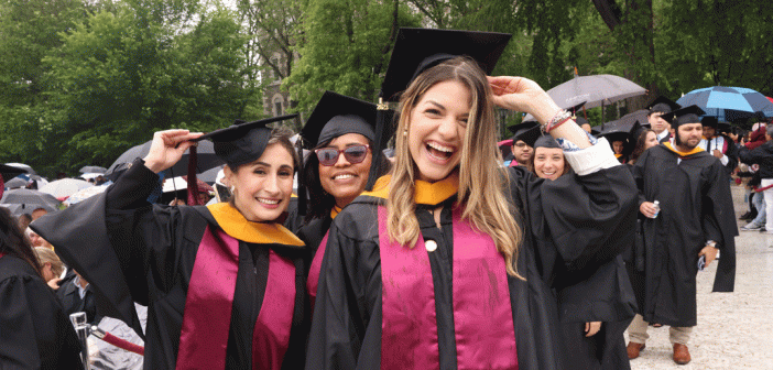 women grads smiling and touching caps