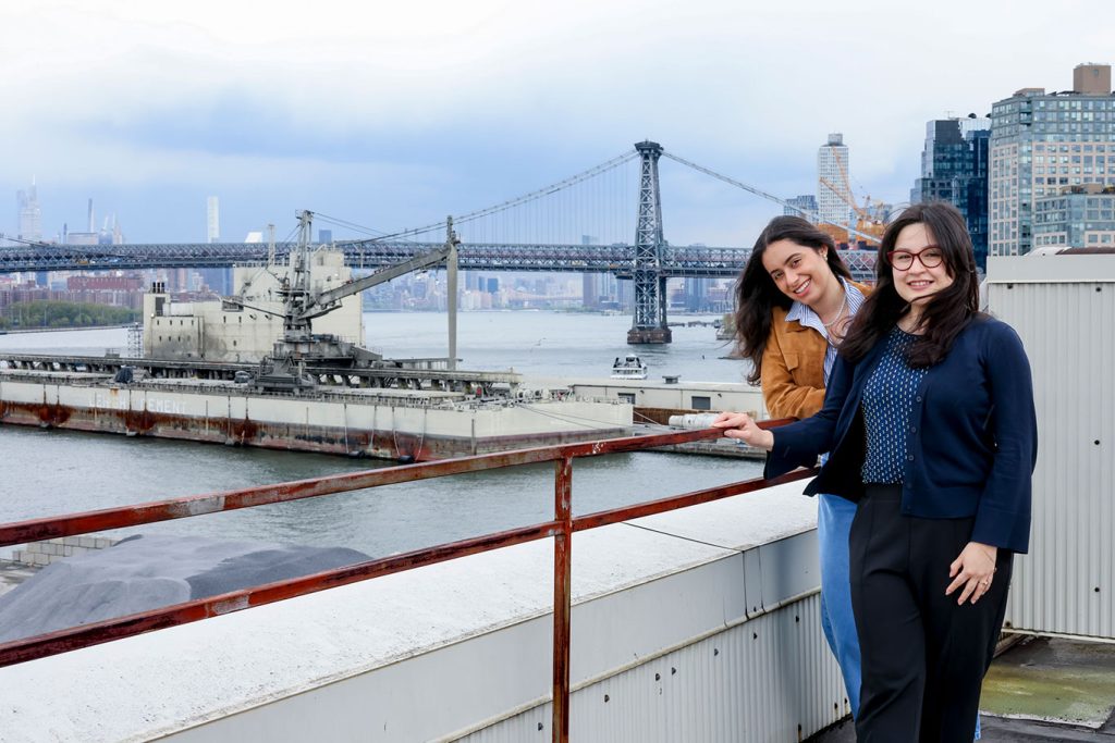 Viviana Villava and Ysabella Escalona standing on the roof of HTIN, with the WIlliamsburg Bridge behind them.