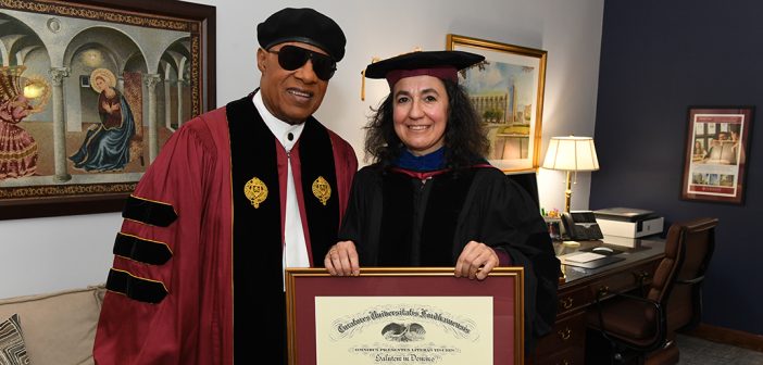 Stevie Wonder with woman holding his framed honorary degree