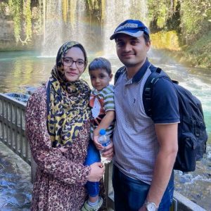 Mishal Ahmed stands with her husband and their 2-year-old son in front of a waterfall.