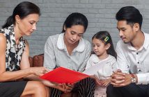 parents and a child look at a piece of paper together with a teacher