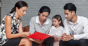 parents and a child look at a piece of paper together with a teacher