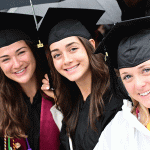 Women graduates under umbrellas at Commencement smiling