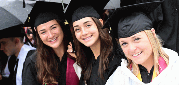Women graduates under umbrellas at Commencement smiling