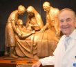 Dr. Michael Brescia poses with a sculpture titled The Compatitor.